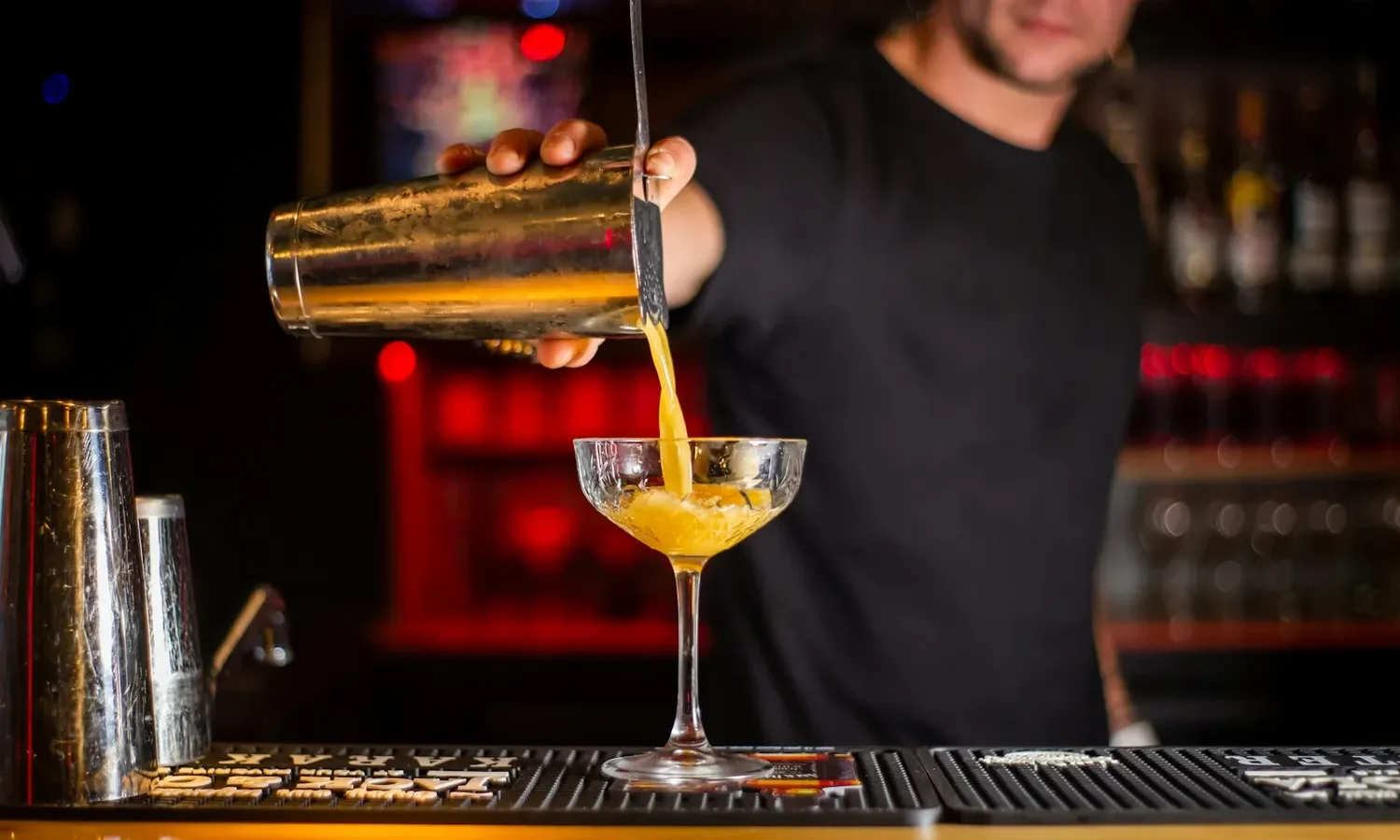 Barman versant un cocktail depuis son shaker