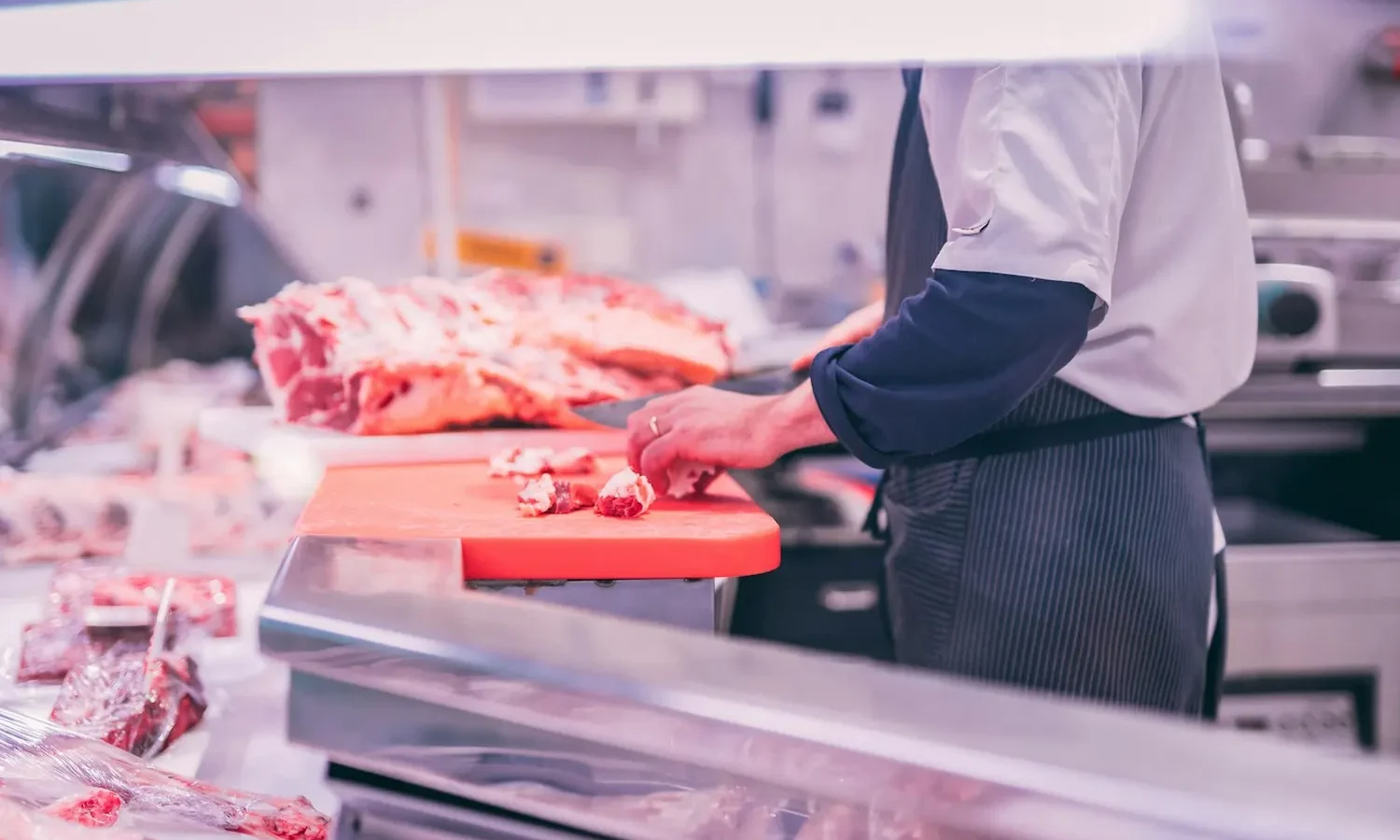 Boucher découpant de la viande sur son étal