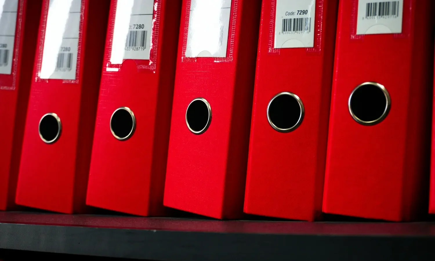 Classeurs rouges alignés sur une étagère