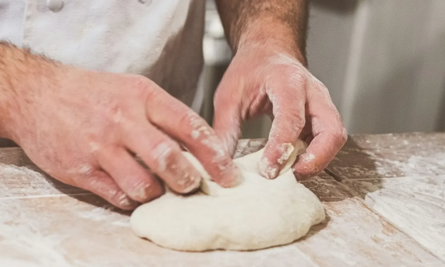 Mains pétrissant une pâte à pain sur un plan fariné